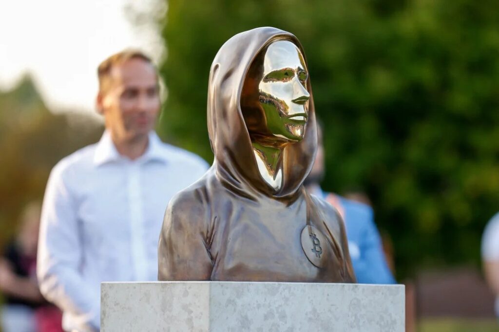 Statue of Satoshi Nakamoto in Budapest, featuring a hooded figure with a reflective face that symbolizes anonymity – The Coinomist
